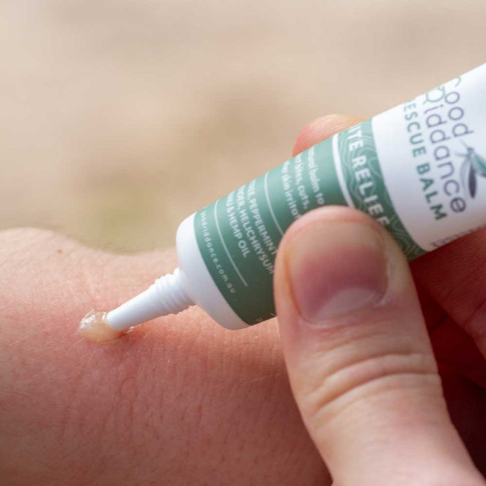 Hand applying a tube of balm to a mosquito bite on skin
