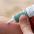 Hand applying a tube of balm to a mosquito bite on skin