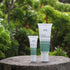 Two tubes of Good Riddance Rescue Balm on a wooden surface with a green leafy background