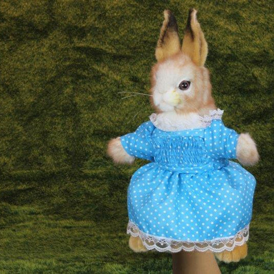 Stuffed rabbit toy in a blue dress with a green background, featuring the Hansa brand.