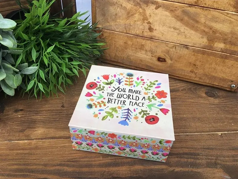 Decorative floral gift box with “You Make the World a Better Place” message on a rustic wooden table