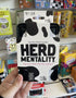 Herd Mentality party game held in store with cow print box and black tray Adventure Awaits