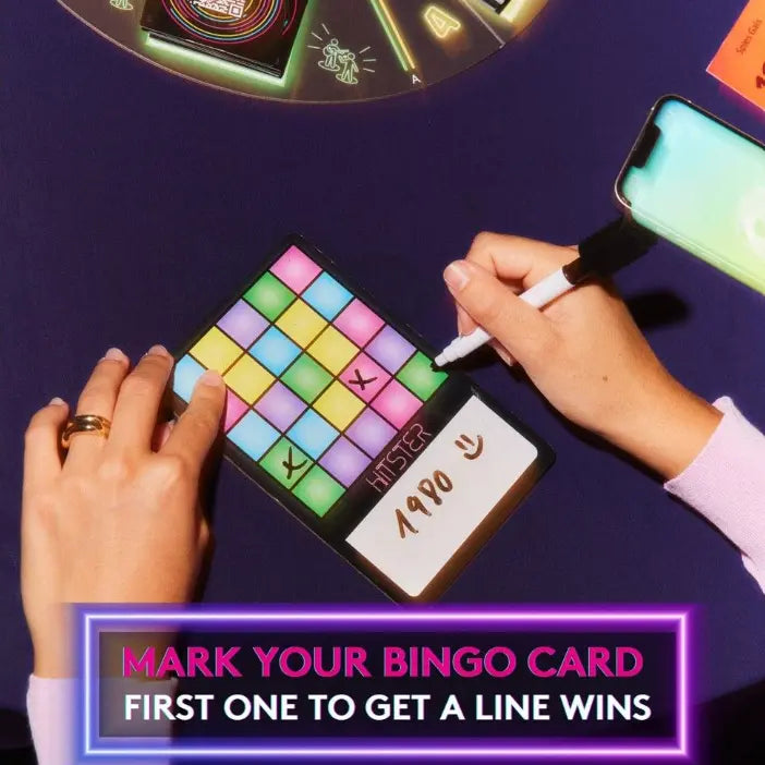 Player marking a colourful HITSTER Music Bingo card while using a phone — Adventure Awaits