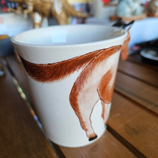 Ceramic mug with horse design on a wooden surface