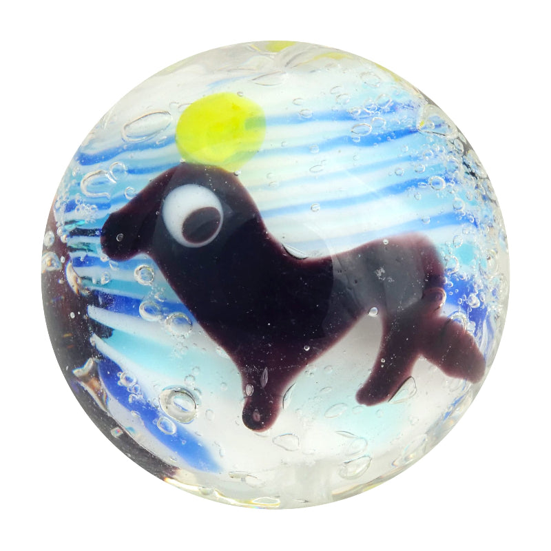 Clear glass marble with black seal design, yellow ball and blue wave-like swirls — Adventure Awaits