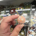 Hand holding a cream glass marble with red, blue and yellow flower-like swirls — Adventure Awaits
