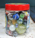 Jar of marbles with a blue die on a marble surface