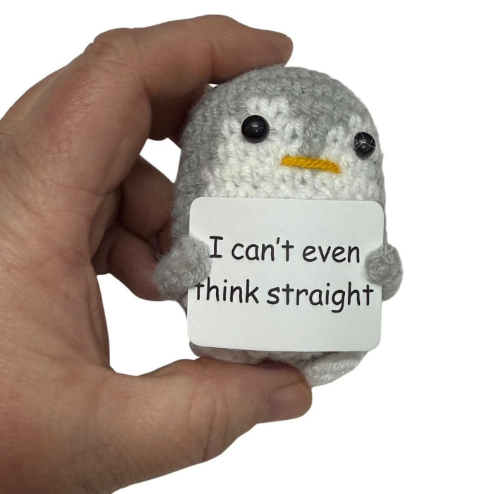 hand holding a handmade crochet penguin plush toy with a funny “I can’t even think straight” sign