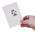 Hand holding a white card with a paw print on a white background