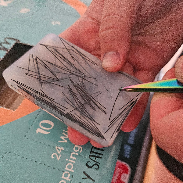 Hand holding a small card with black lines against a blurred background