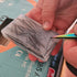 Hand holding a small card with black lines against a blurred background
