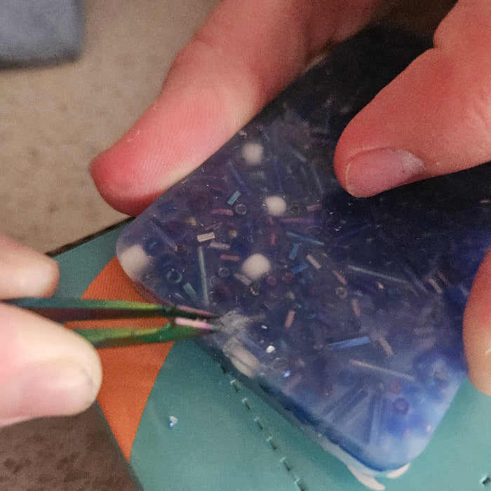 Person using a tool to remove nails from a blue plastic container.