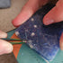Person using a tool to remove nails from a blue plastic container.