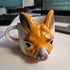 Ceramic mug shaped like a kangaroo with a handle on a white surface.