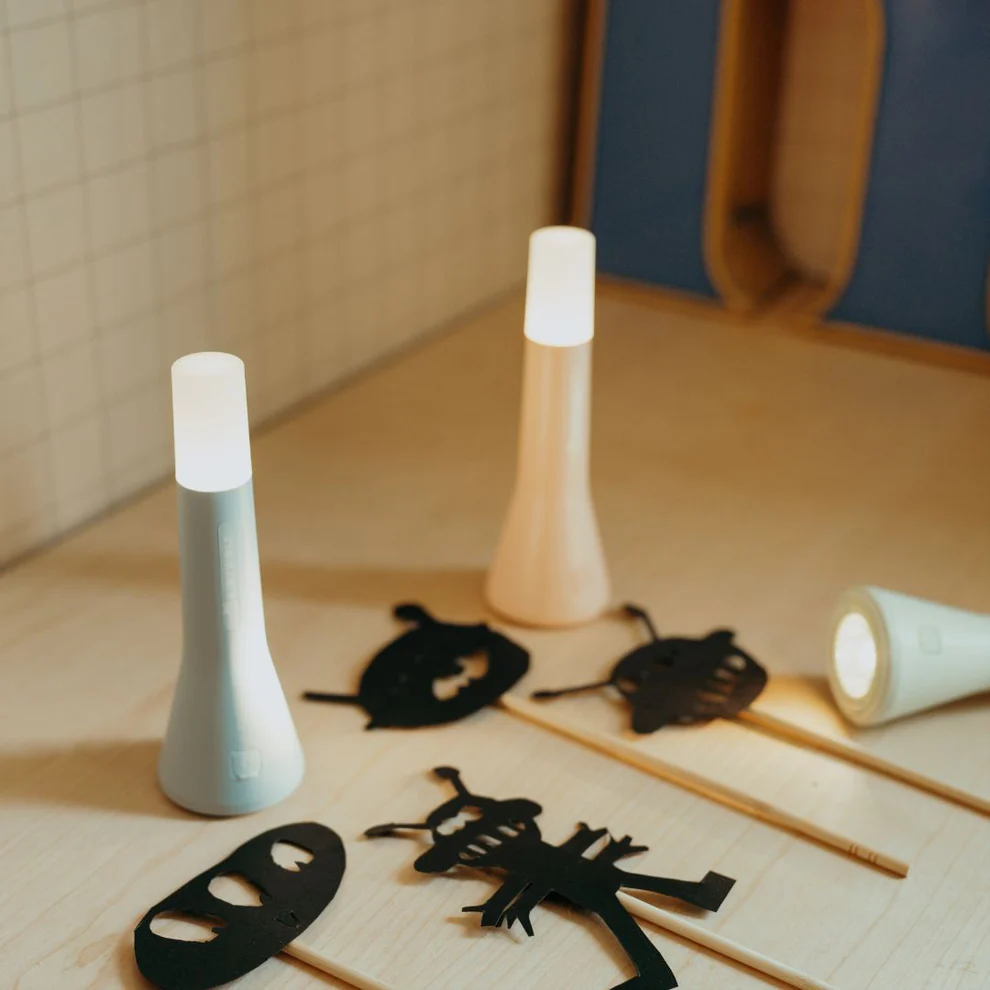 Adventure Awaits portable LED night lights with glowing tops beside shadow puppet cut-outs on a tabletop