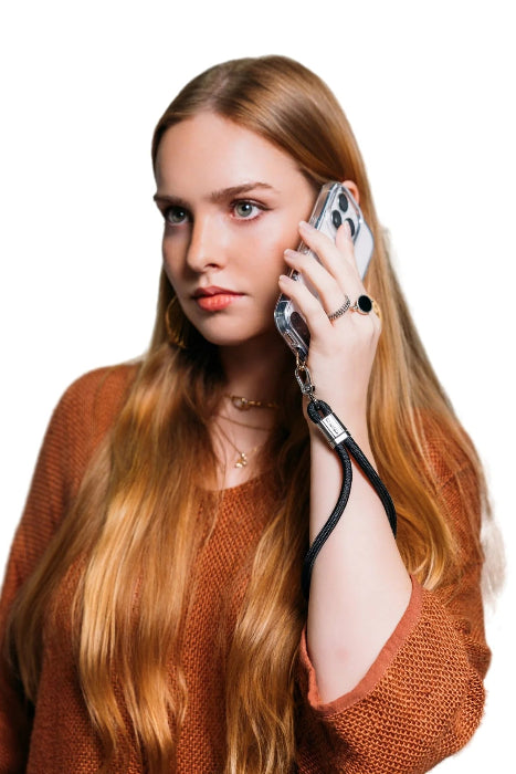 Woman takes a call with her phone secured by a black wrist strap, Adventure Awaits