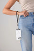 Woman wears a black phone wrist strap carrying her phone beside blue jeans, Adventure Awaits