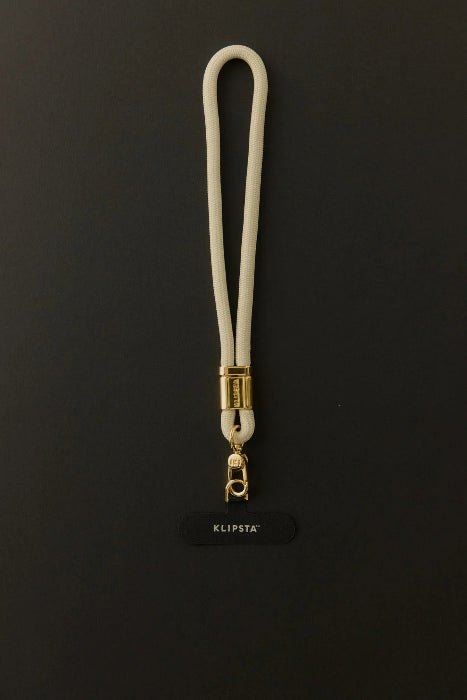 Light grey Klipsta phone wrist strap with gold clasp and phone connector tab, Adventure Awaits