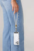 Woman holds a phone by a light grey wrist strap with gold clasp beside blue jeans, Adventure Awaits