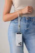 Woman carries a phone from a light grey wrist strap with gold clasp beside blue jeans, Adventure Awaits