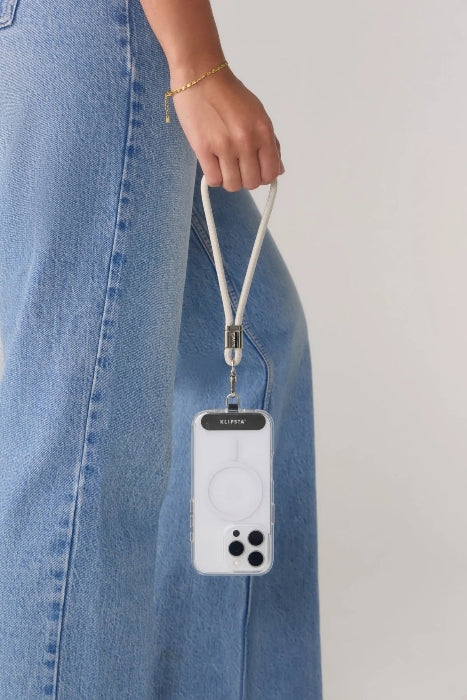 Woman carries a phone by a white wrist strap beside a blue denim skirt, Adventure Awaits