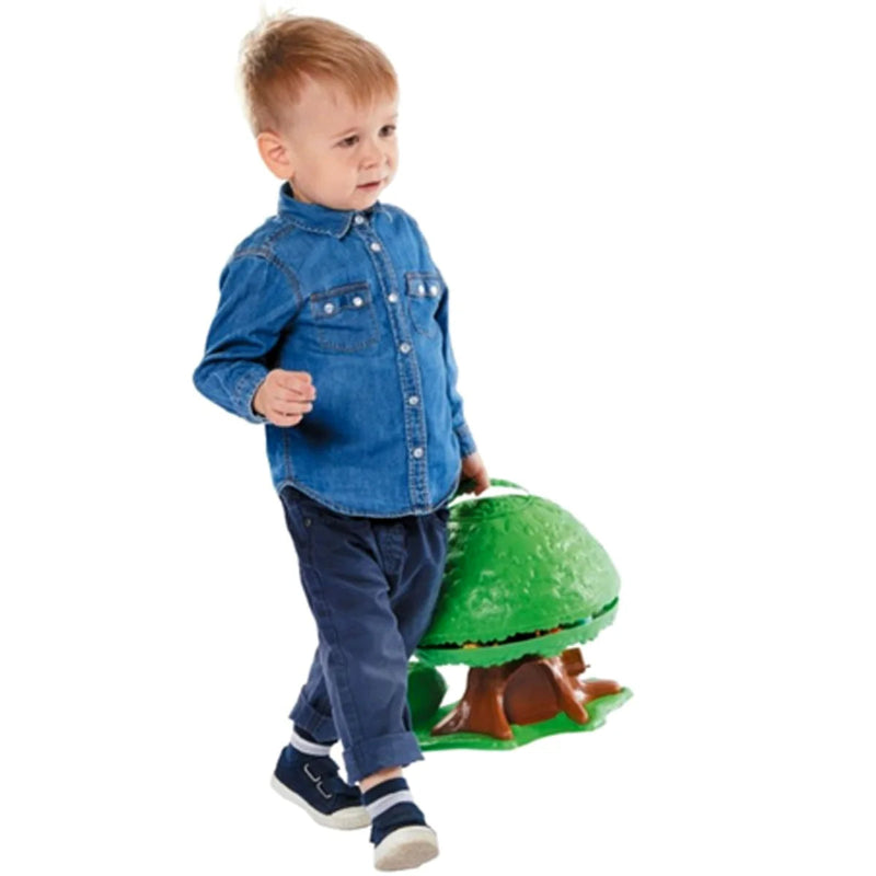 Child in a denim shirt and pants holding a green dinosaur toy on a white background