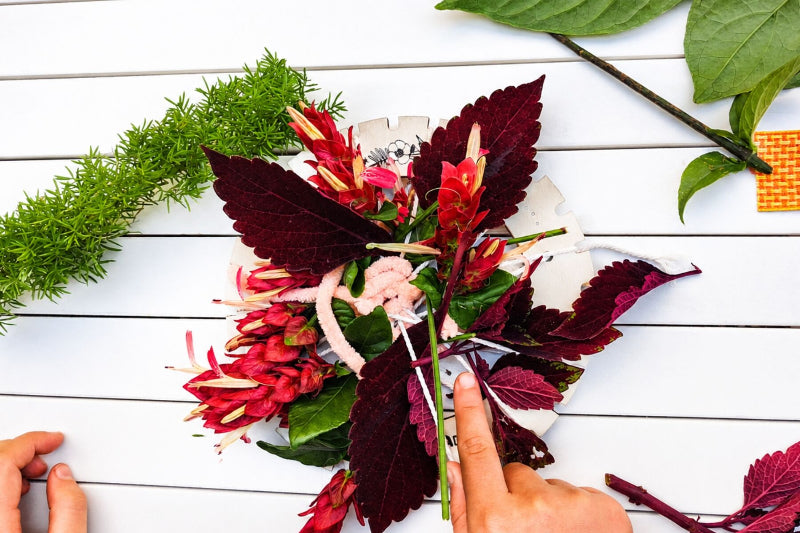 Child creating Koala Dream Bush Blooms nature weaving craft with leaves and flowers — Adventure Awaits