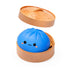 Blue lucky bao dumpling-shaped container with a smiling face squishy on a beige lid, on a white background