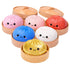 Set of colourful Lucky Bao bun-shaped squishies with faces in a steamer-like container on a white background