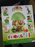 The retail packaging box for the Klorofil Magic Tree toy set, photographed on a dark surface. The box features a colorful illustration of the green treehouse with a brown trunk, surrounded by small inset photos of children playing with the toy and a row of included pieces at the bottom.