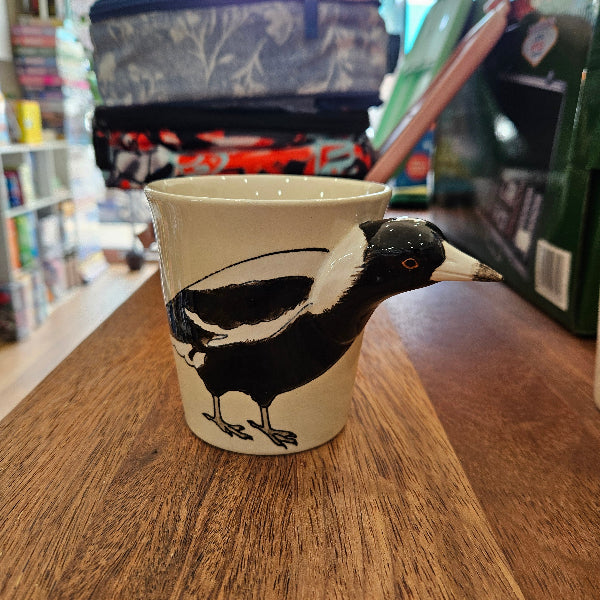 Ceramic mug with a magipie design on a wooden surface.