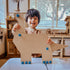 Smiling child holds a cardboard dinosaur built with blue Makedo connectors during creative play — Adventure Awaits