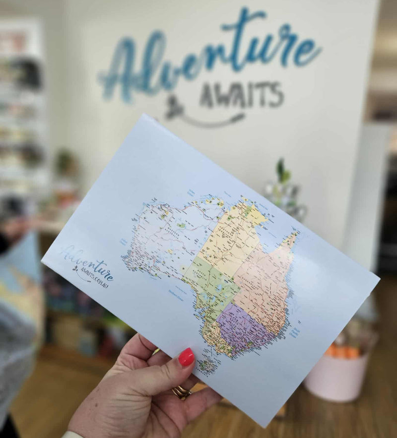 Map of Australia held by a hand with 'Adventure Awaits' text in the background