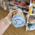 Person holding a rolled-up fabric product with a store shelf in the background