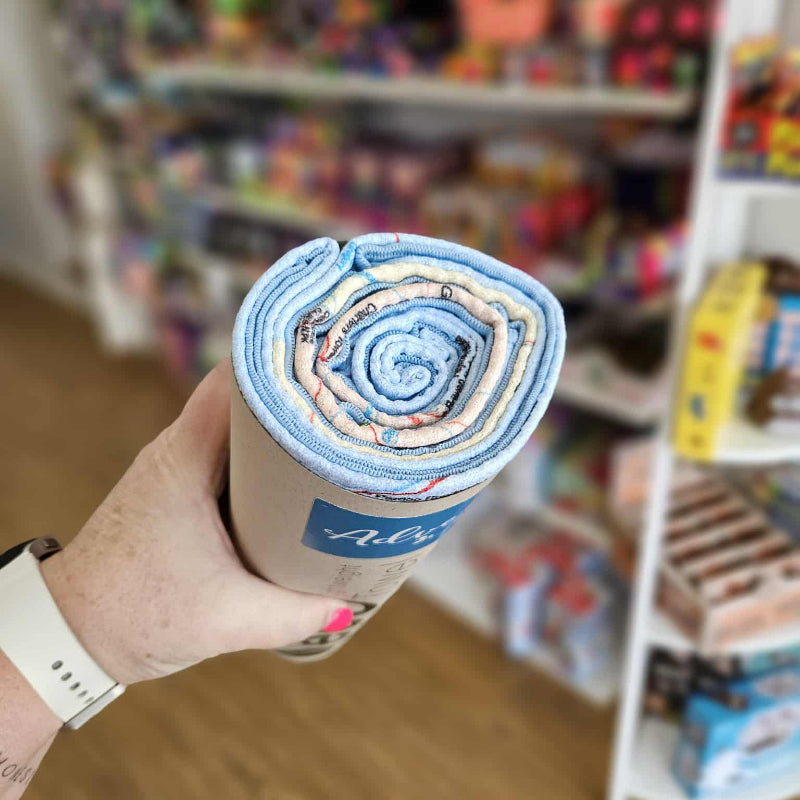 Hand holding a cylindrical product with a blue label in a store setting