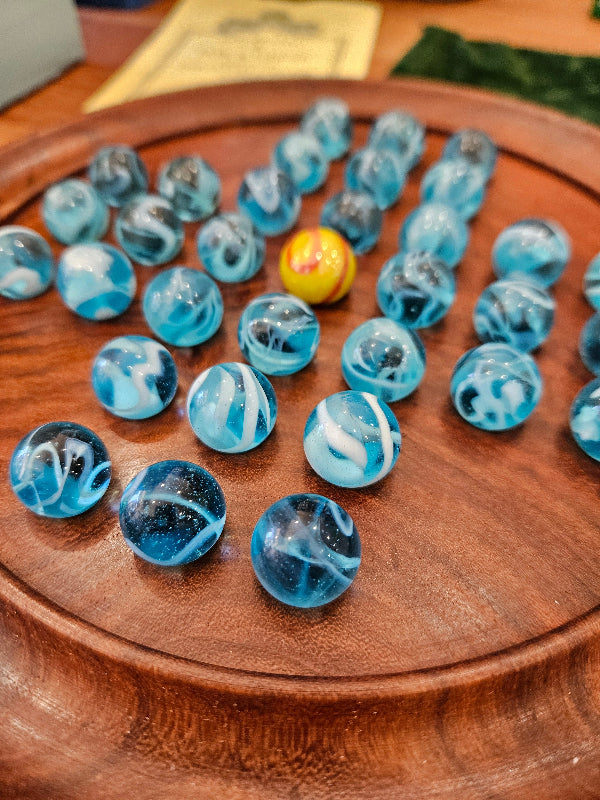 Blue marbles with a yellow one on a wooden surface solitaire game 
