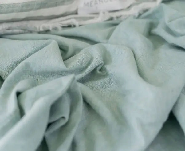 Close up of soft sage green fabric with lightweight texture and relaxed natural folds