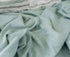Close up of soft sage green fabric with lightweight texture and relaxed natural folds