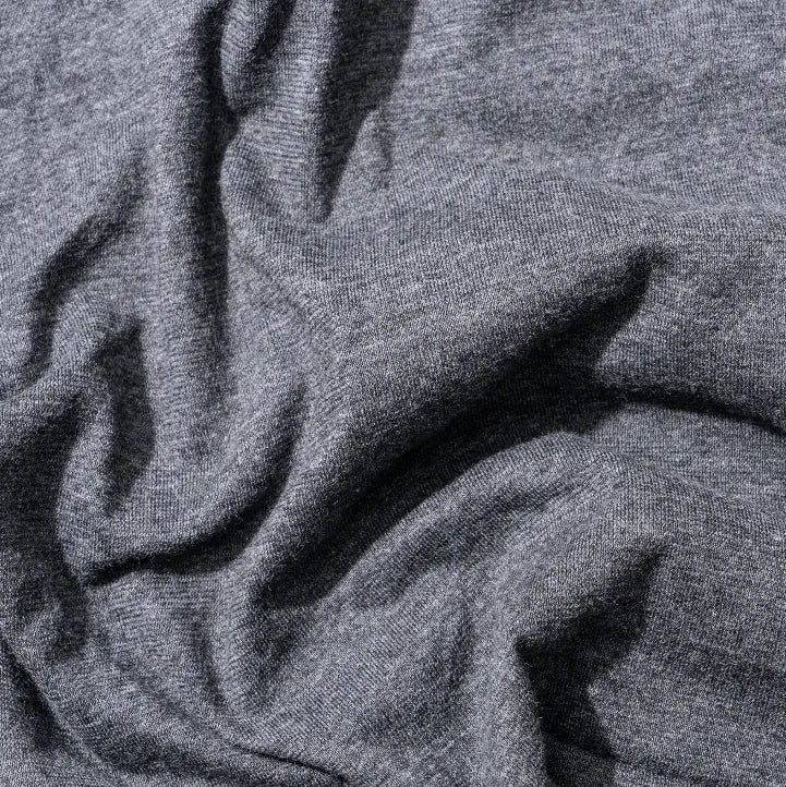 Close up of soft charcoal grey fabric with a textured knit finish and natural draped folds