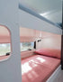 Modern caravan bunk beds with pink bedding, window lighting and compact family travel interior design