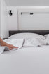 Hands smoothing MeanderWild grey flannelette caravan sheets — soft warm bedding for cool nights on the road — Adventure Awaits
