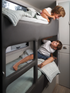 Two children on a compact bunk bed in a small living space.