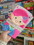 Pink and blue mittens with a cartoon character held in front of a bookshelf.