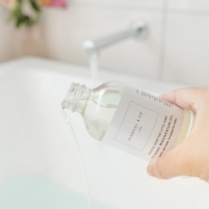 Pouring Mindful and Co calming magnesium oil into bath water, gentle sleep support for babies and children at home or travel Adventure Awaits