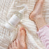 Mindful and Co calming magnesium oil spray bottle beside child’s feet on soft blanket, gentle sleep support for babies and children at home or travel Adventure Awaits