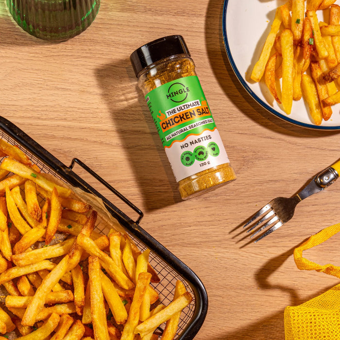 Mingle The Ultimate Chicken Salt 130g bottle styled beside golden hot chips on a wooden table — Adventure Awaits
