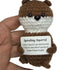 hand holding a handmade crochet squirrel plush toy with a funny “Spiralling Squirrel” quote sign