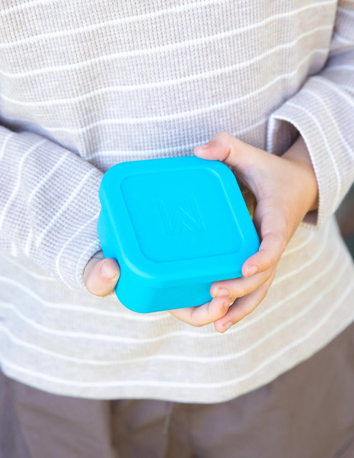 Child holding a blue Montiico snack container with fitted lid — Adventure Awaits