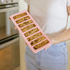 Person holding a pink silicone mold with baked bars in a kitchen setting