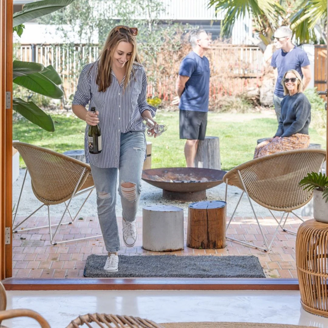 Woman walking into a backyard with friends around a fire pit